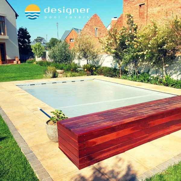 designer pool covers A wooden bench sits next to a pool.