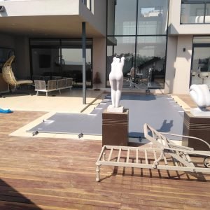 designer pool covers A wooden deck with a statue in front of a house.