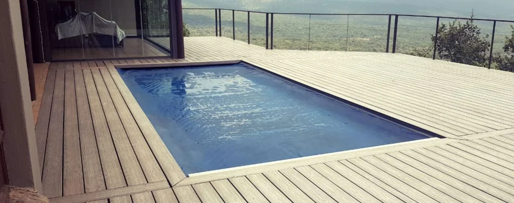 designer pool covers A swimming pool on a wooden deck with pool covers overlooking the mountains.