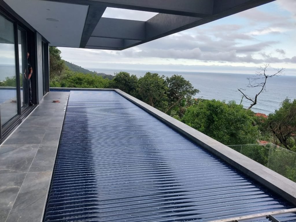 designer pool covers A swimming pool with automatic pool covers and a view of the ocean.